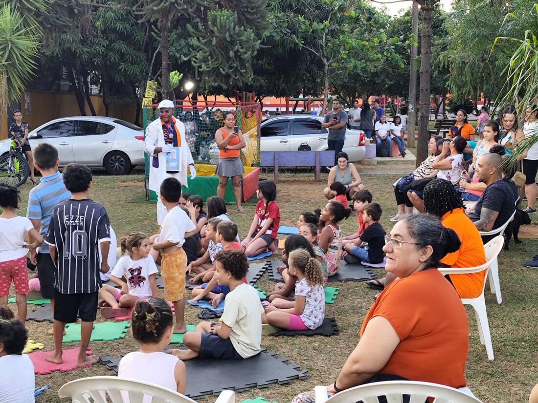 Famílias sentadas na grama assistindo à apresentação