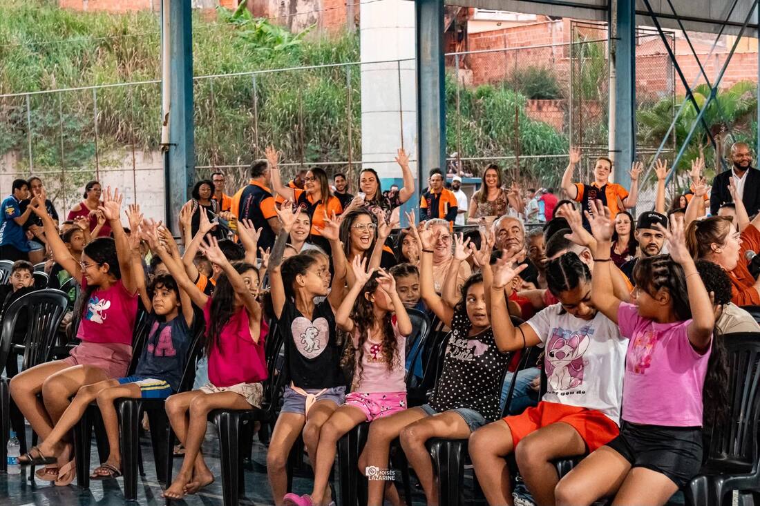 Crianças com os braços erguidos durante a apresentação
